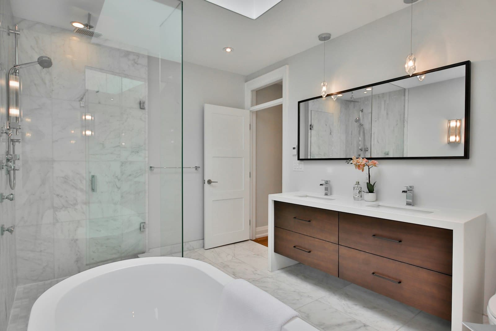 Badkamer met ligbad, inloopdouche en houten meubel